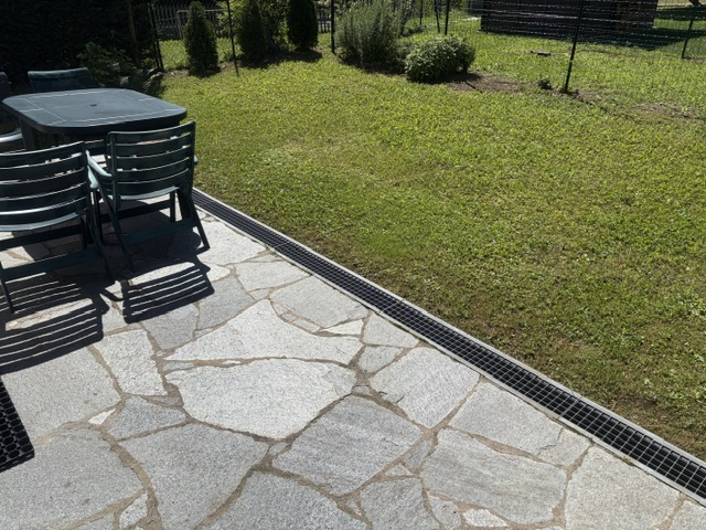 Patio in pietra con area pranzo esterna e giardino